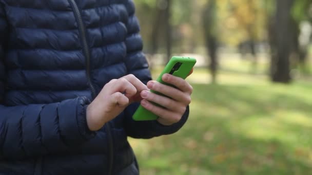 スマートフォンを持っている若い男の手のクローズアップと指でタッチスクリーンにスワイプします。男は電話のメッセージを読むか、彼の携帯電話のためのアプリをダウンロード. - 映像、動画