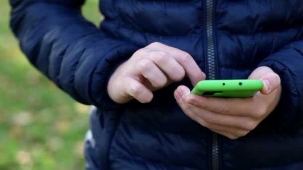 Detailní záběr ruky mladíka, který drží smartphone a prstem šlehá po dotykovém displeji. Muž, který čte telefonní zprávu nebo stahuje aplikaci pro svůj mobilní telefon. - Záběry, video