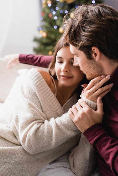 couple with closed eyes, in warm sweaters hugging at home - Фото, зображення