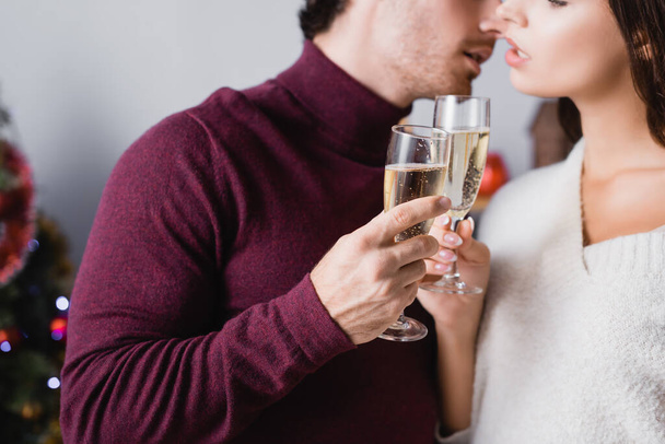 cropped view of glasses with champagne in hands of couple on blurred background - Foto, imagen