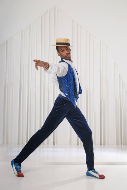 A black guy in stage clothes is dancing in a bright room. - Photo, image