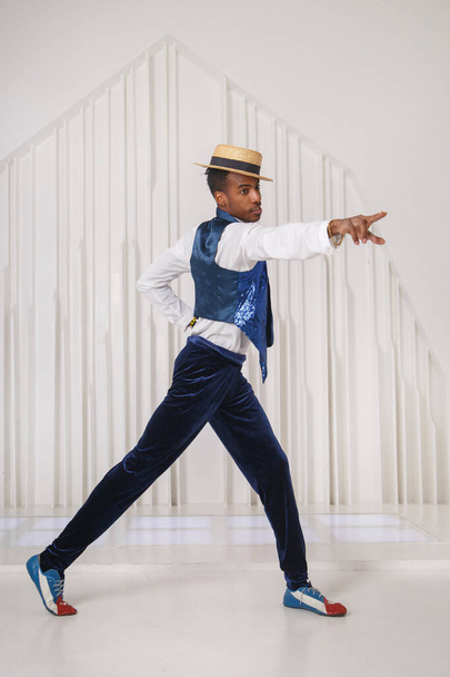 A black guy in stage clothes is dancing in a bright room. - Fotoğraf, Görsel