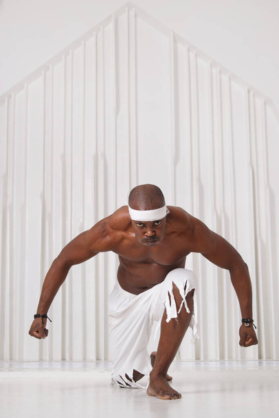 Black man afro dancer in white shorts and bandages in a bright room. - 写真・画像