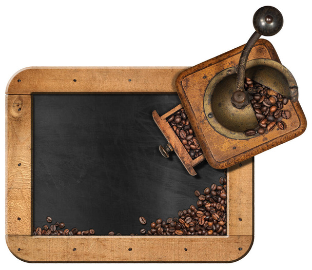 Oude handmatige koffiemolen en een schoolbord met kopieerruimte en gebrande koffiebonen, geïsoleerd op witte achtergrond. - Foto, afbeelding