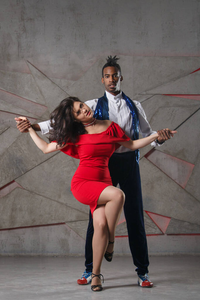 A white girl in a red dress and a black guy are dancing salsa. - Foto, Bild