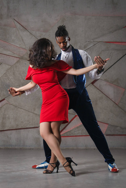 A white girl in a red dress and a black guy are dancing salsa. - Φωτογραφία, εικόνα