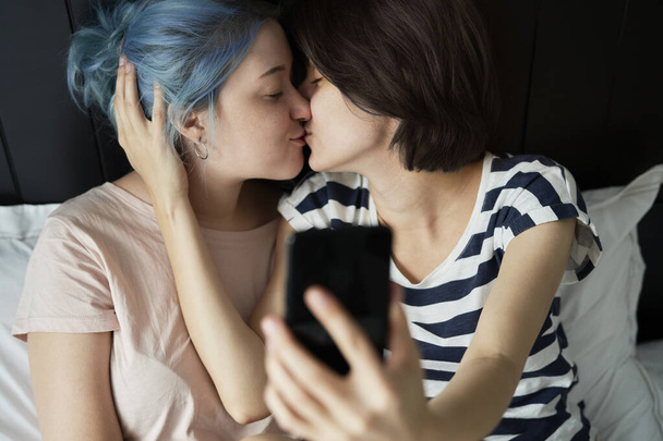 Lesbian couple taking a selfie while kissing                                - Фото, зображення