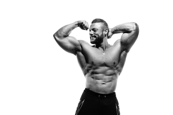 Black-white portrait of a smiling athletic man with a naked torso demonstrates biceps isolated on a white background. - Foto, imagen