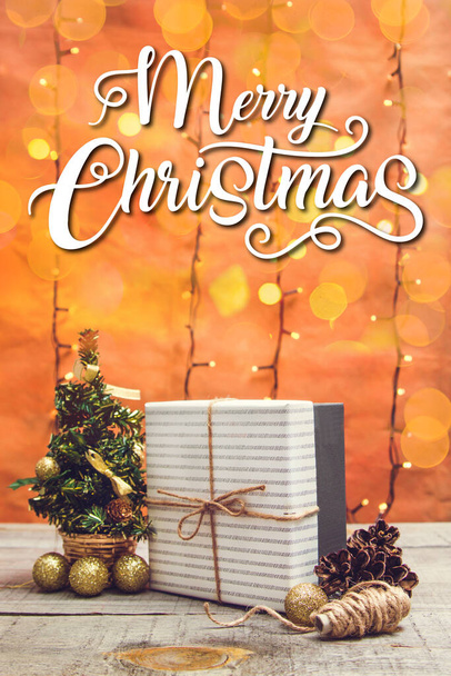 Ajándék doboz karácsonyi dekorációval és bokeh fények egy fa asztalon - Fotó, kép