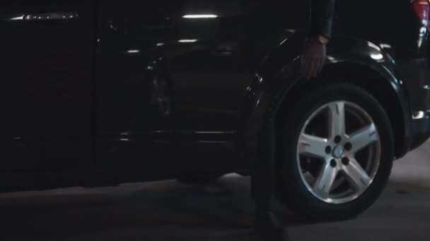 Inclinando-se imagens de homem barbudo brutal em óculos escuros saindo do grande carro preto no estacionamento subterrâneo com esquadrão de criminosos em negociação - Filmagem, Vídeo