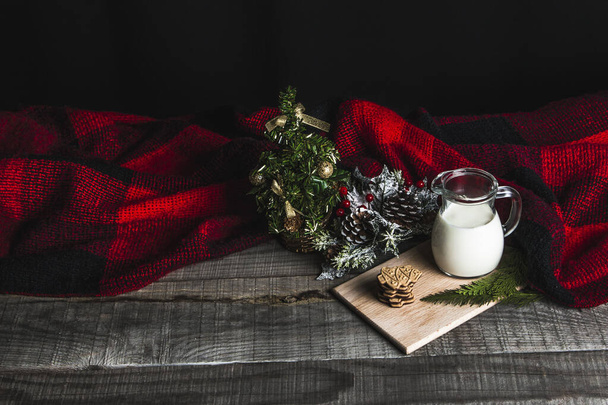Leche fresca y galletas de Navidad con decoraciones navideñas en una mesa de madera - Foto, Imagen