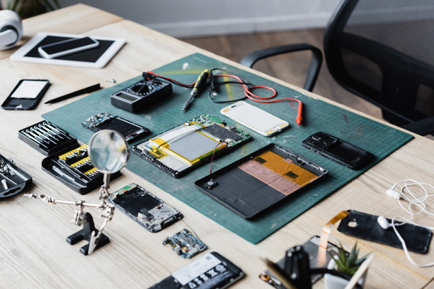 Flat lay of disassembled parts of devices, multi meter, screwdriver and magnifier on workplace - Foto, Imagen