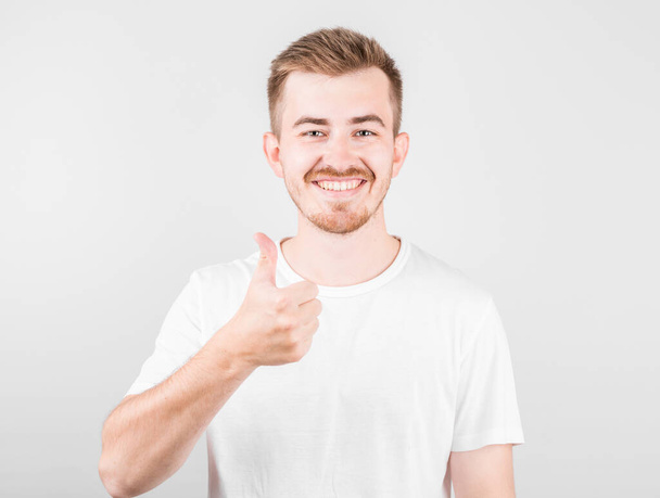 Pleased good-looking happy male showing thumbs up and smiling broadly, giving positive feedback. - Foto, imagen