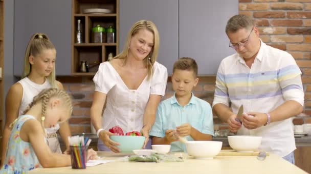 Rodinné vaření doma. Šťastní rodiče, tři děti připravují slavnostní večeři - Záběry, video