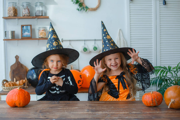 Két kislány boszorkányjelmezben Halloweenkor, a konyhában. - Fotó, kép