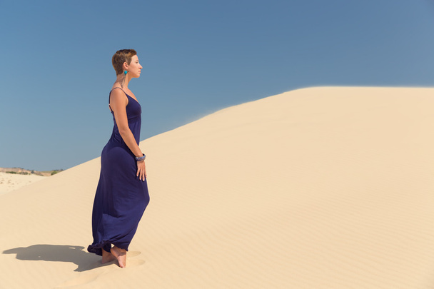 Beautiful woman in blue dress in sand dune - Fotó, kép