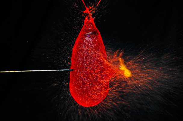 Captura de alta velocidade de peças de balão vermelho e gotas de água salpicando - Foto, Imagem