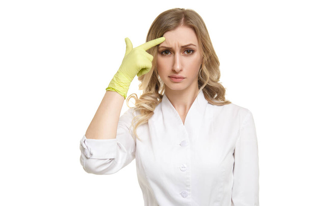 Girl doctor points his finger to the wrinkles on his forehead isolated on a white background. - Фото, изображение