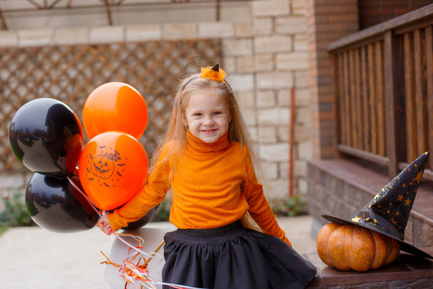 cute little girl sitting on porch with balloons, Halloween concept - Fotoğraf, Görsel