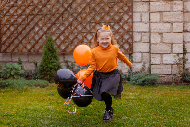 little girl runs joyfully across the lawn in balloons Halloween party - Foto, immagini