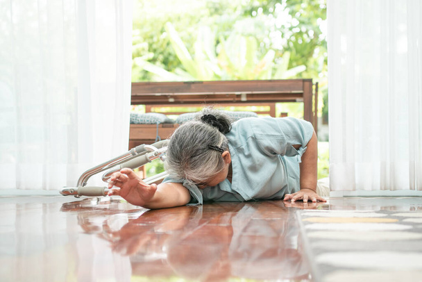 Azjatycka starsza kobieta upadła na podłogę w domu po tym, jak potknęła się o drzwi i płakała z bólu prosząc kogoś o pomoc. Pojęcie ubezpieczenia emerytalnego i opieki zdrowotnej - Zdjęcie, obraz