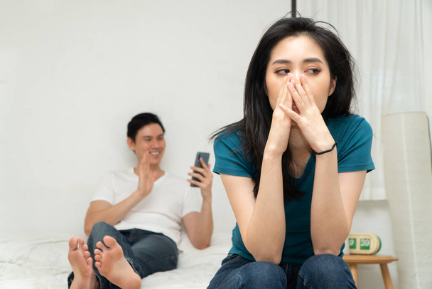 Mujer asiática infeliz en la cama y sentirse aburrido y gruñón su marido porque cansado de su marido que la ignora y utiliza el teléfono inteligente todo el tiempo. Concepto de problema de relación de la tecnología - Foto, Imagen