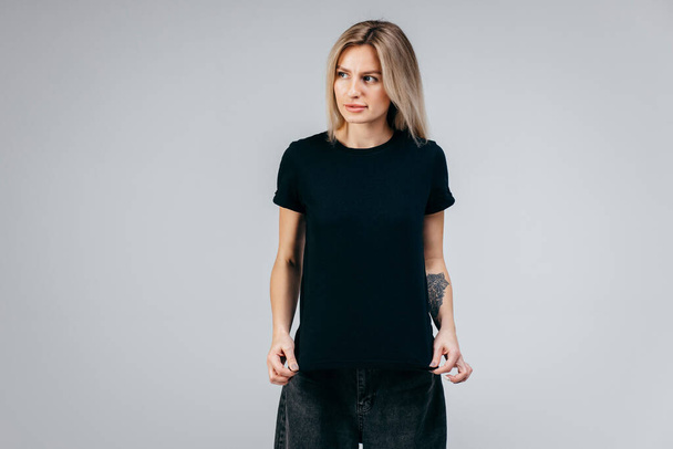 Tyylikäs blondi tyttö yllään musta t-paita poseeraa studiossa - Valokuva, kuva