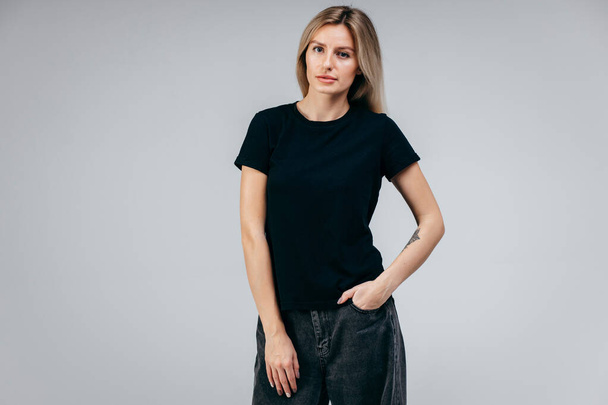 Menina loira elegante vestindo t-shirt preta posando em estúdio - Foto, Imagem