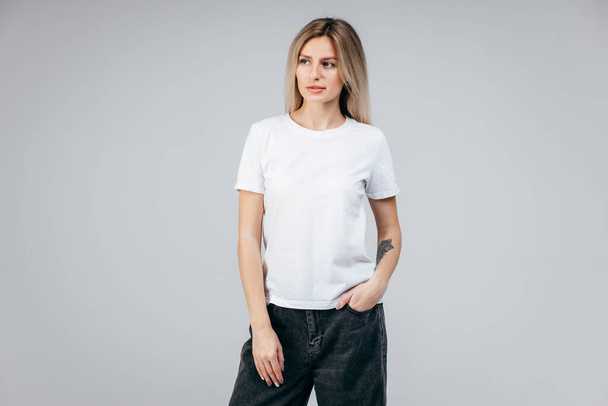 Menina loira elegante vestindo t-shirt branca posando em estúdio - Foto, Imagem
