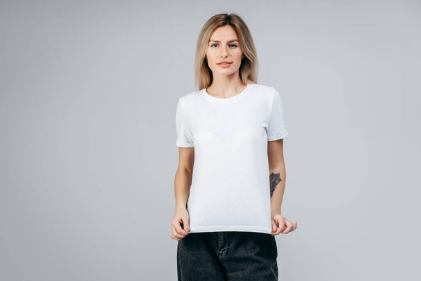 Menina loira elegante vestindo t-shirt branca posando em estúdio - Foto, Imagem