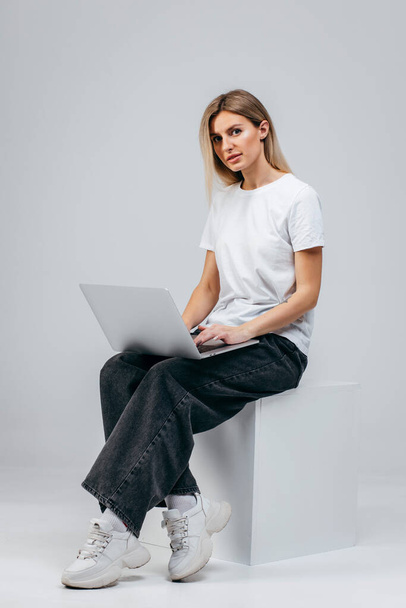 Moderni tyttö valkoisessa t-paidassa läppäri studiossa. Vapaa luovuus - Valokuva, kuva