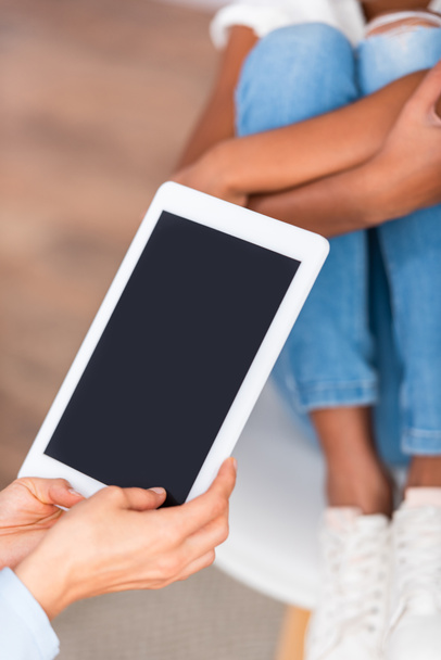 Vista cortada de psicólogo com tablet digital perto de menina americana africana borrada em segundo plano - Foto, Imagem