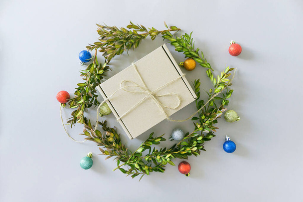 Boîte cadeau artisanale sur fond pastel avec brunchs en buis et boules décoratives. Cadeau de Noël. Pose plate. Vue du dessus - Photo, image