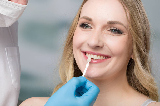 歯を漂白するための歯の通気口を確認するために女性の口で日陰ガイドを使用して歯科医の閉鎖 - 写真・画像