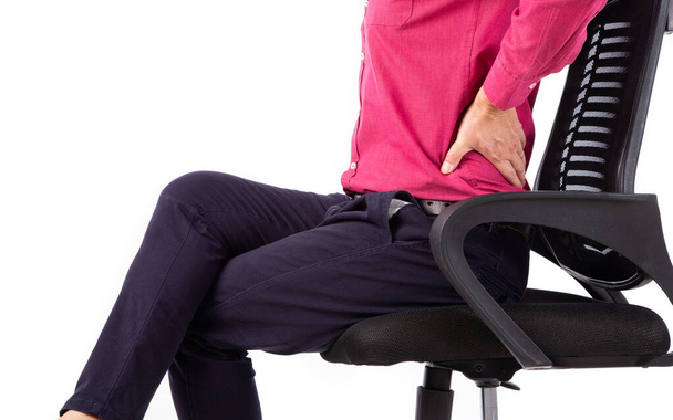 Liikemies, jolla on selkäkipuja ja joka istuu työtuolissa. Kivunlievityksen käsite - Valokuva, kuva