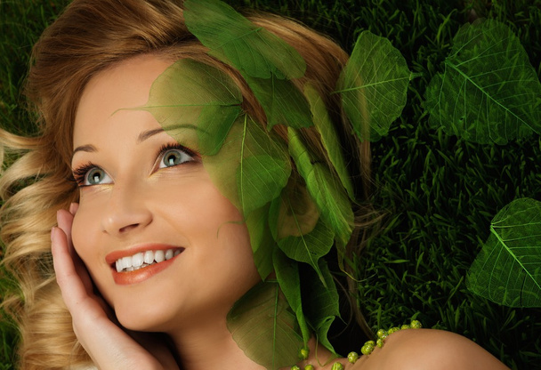 Mujer joven sonriente acostada en una hierba fresca de primavera
  - Foto, Imagen