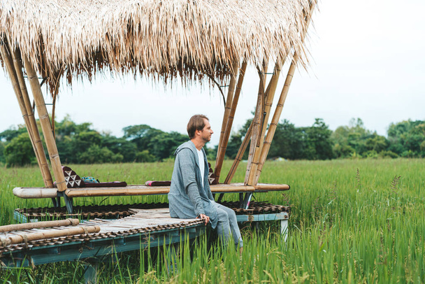 Man in love is sitting at bamboo bridge in rice field - Zdjęcie, obraz