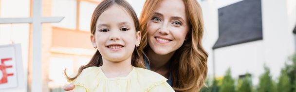 Portrait of happy mother and daughter looking at camera on blurred background, banner - Foto, imagen