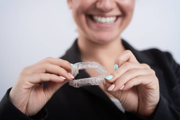 A woman is holding a transparent plastic mouth guard. Orthodontists bite correction device - Фото, изображение