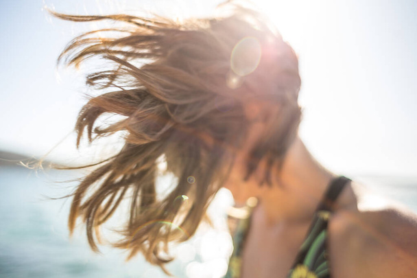 Nuori nainen meren pohjassa. Hiukset puhaltavat tuulessa. Punatukkainen tyttö rannikolla. Iloinen tyttö. - Valokuva, kuva