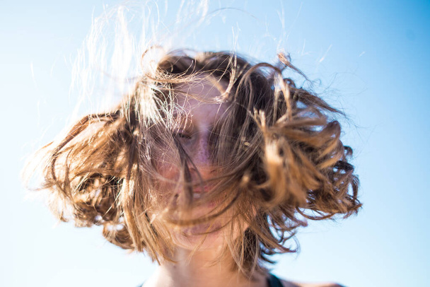 Портрет усміхненої дівчини з веснянками. Волосся дує на вітрі. Відпочинок на березі
. - Фото, зображення