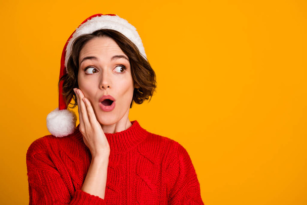 Closeup photo of pretty excited lady celebrate winter holidays family open mouth look empty space arm cheekbone wear santa claus cap red knitted sweater isolated yellow color background - Photo, image