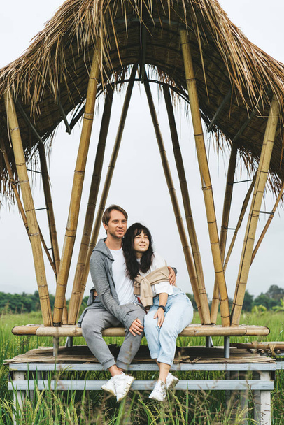 Couple in love is sitting at bamboo bridge in rice field - Foto, imagen