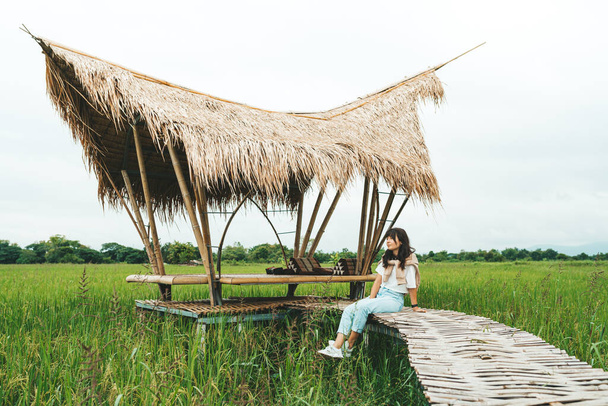 Woman is sitting at bamboo bridge in rice field - Fotoğraf, Görsel