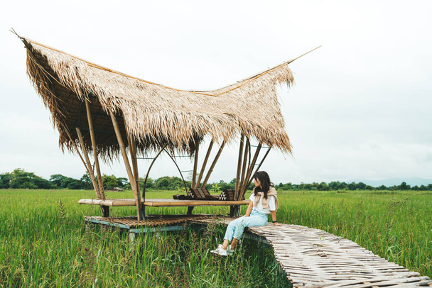 Woman is sitting at bamboo bridge in rice field - Photo, image