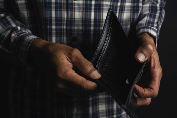 Close-up for a man standing and holding empty wallet. Wallet out of money. - Photo, Image