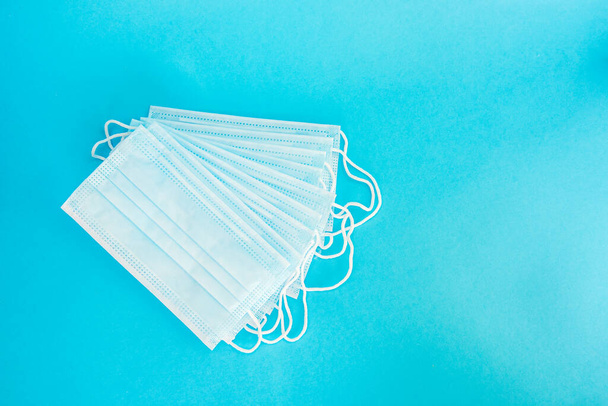 Blue medical face mask isolated on light blue background. A beautiful stack of disposable medical masks on a blue background. Place for text - Fotoğraf, Görsel