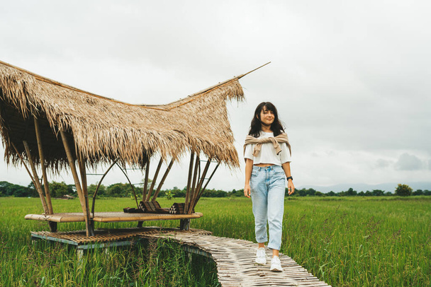 Woman is walking by bamboo bridge in rice field - Fotoğraf, Görsel