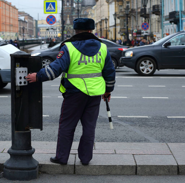 Police officer of the road patrol service regulates traffic by manually controlling the traffic light, Nevsky Prospekt, Saint Petersburg, Russia, October 2020 - Zdjęcie, obraz
