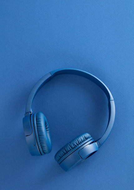 青い背景の青いヘッドフォン - 写真・画像